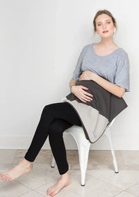 Pregnant woman seated with a Mountain Charcoal Belly Armor blanket over her belly