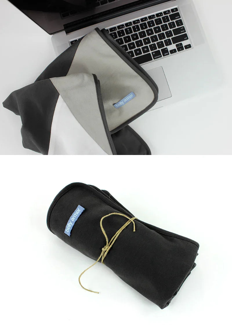 Belly Armor charcoal belly blanket folded beside a laptop and rolled for travel