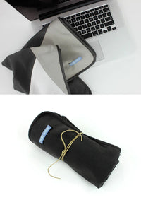 Belly Armor charcoal belly blanket folded beside a laptop and rolled for travel