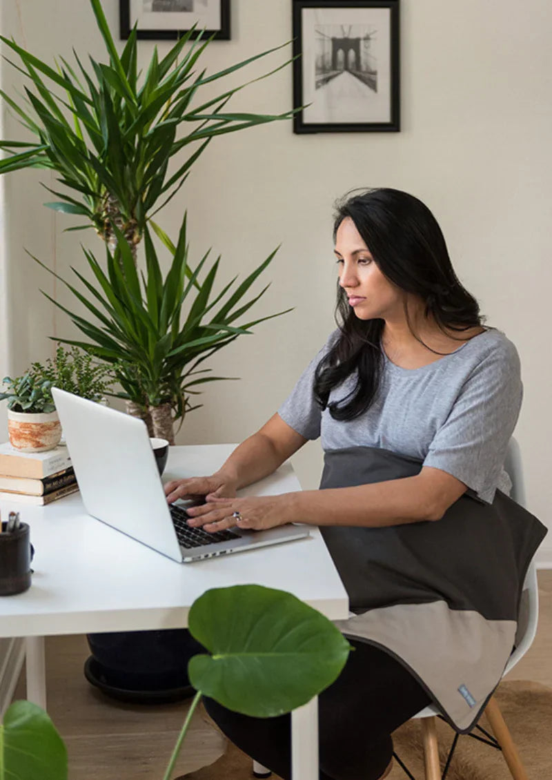 Pregnant woman using a laptop with a charcoal Belly Armor blanket over her lap
