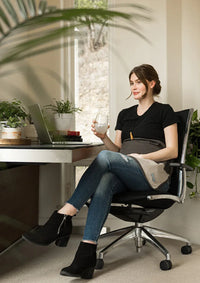 Pregnant woman seated at a desk with a charcoal Belly Armor blanket over her belly