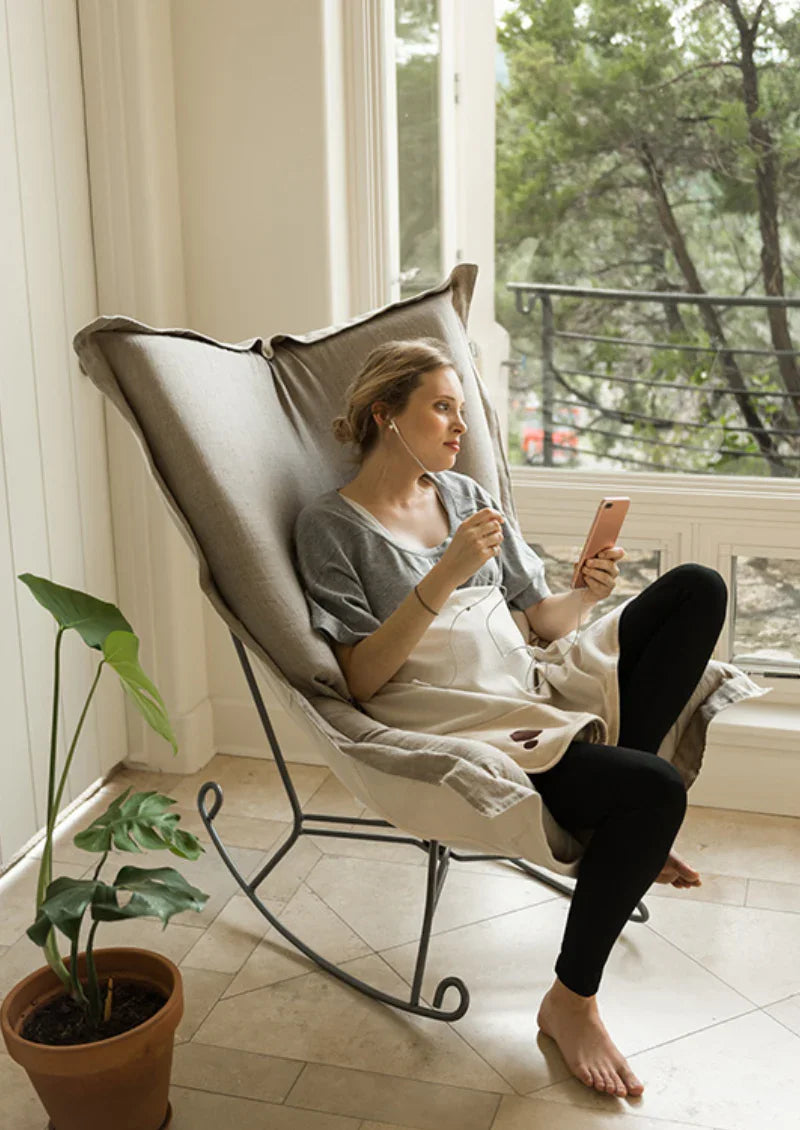 Pregnant woman reading by a window with a Belly Armor organic blanket on her lap