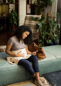 Pregnant woman sitting beside her child with an organic Belly Armor blanket on her lap