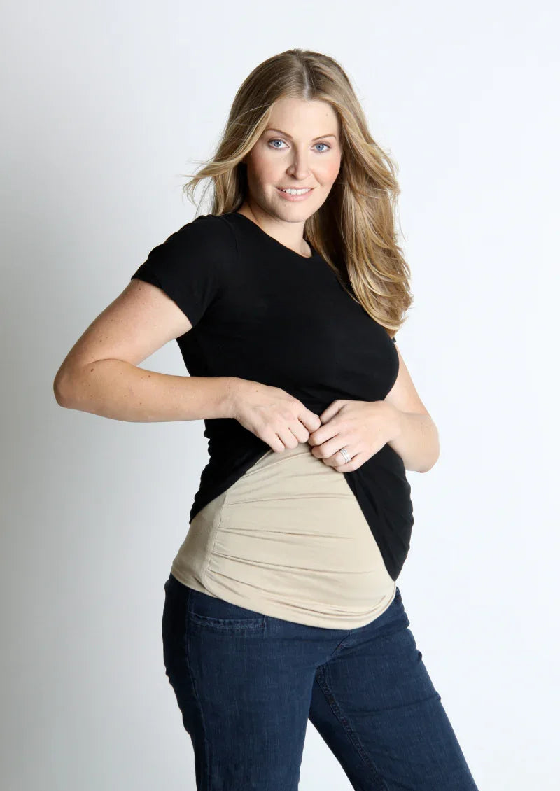 Woman lifting her shirt to show a beige Belly Armor adjustable EMF belly band