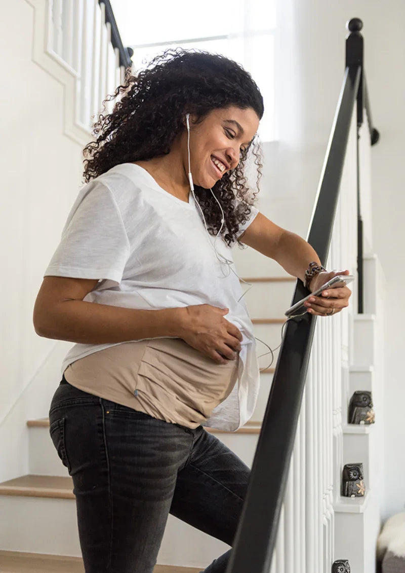 Pregnant woman using her phone while wearing an adjustable Belly Armor EMF belly band