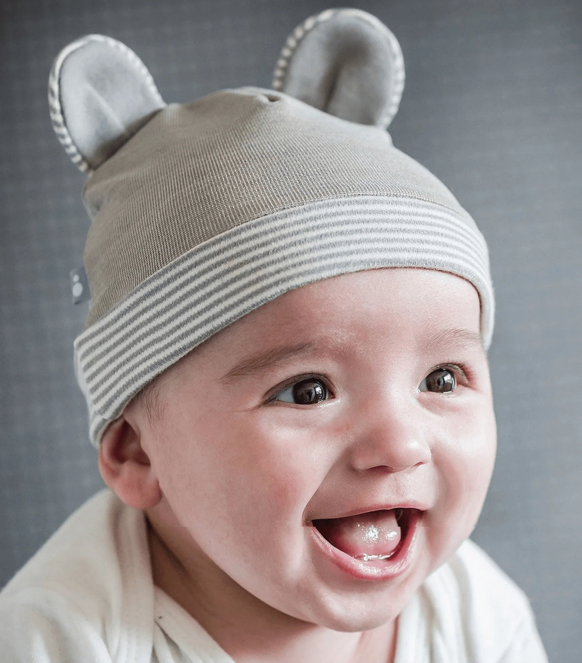 Baby wearing a gray Belly Armor organic cotton EMF protection hat with rounded ears