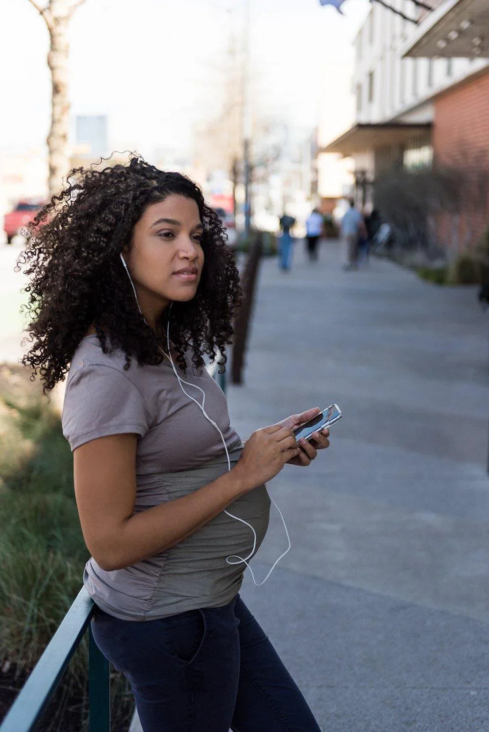Woman wearing a gray Belly Armor EMF maternity tee while using her phone