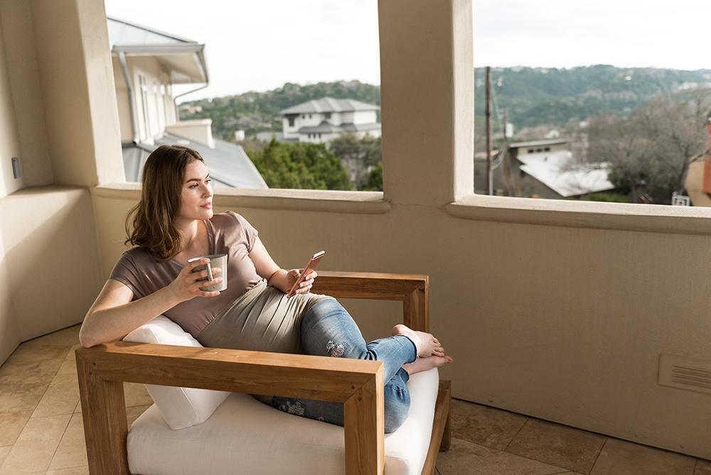 Woman relaxing by a window wearing a Belly Armor ruched maternity tee
